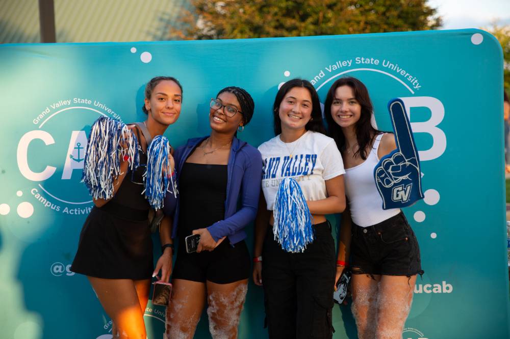 students posing in front of backdrop at Laker Kickoff photo booth outdoors